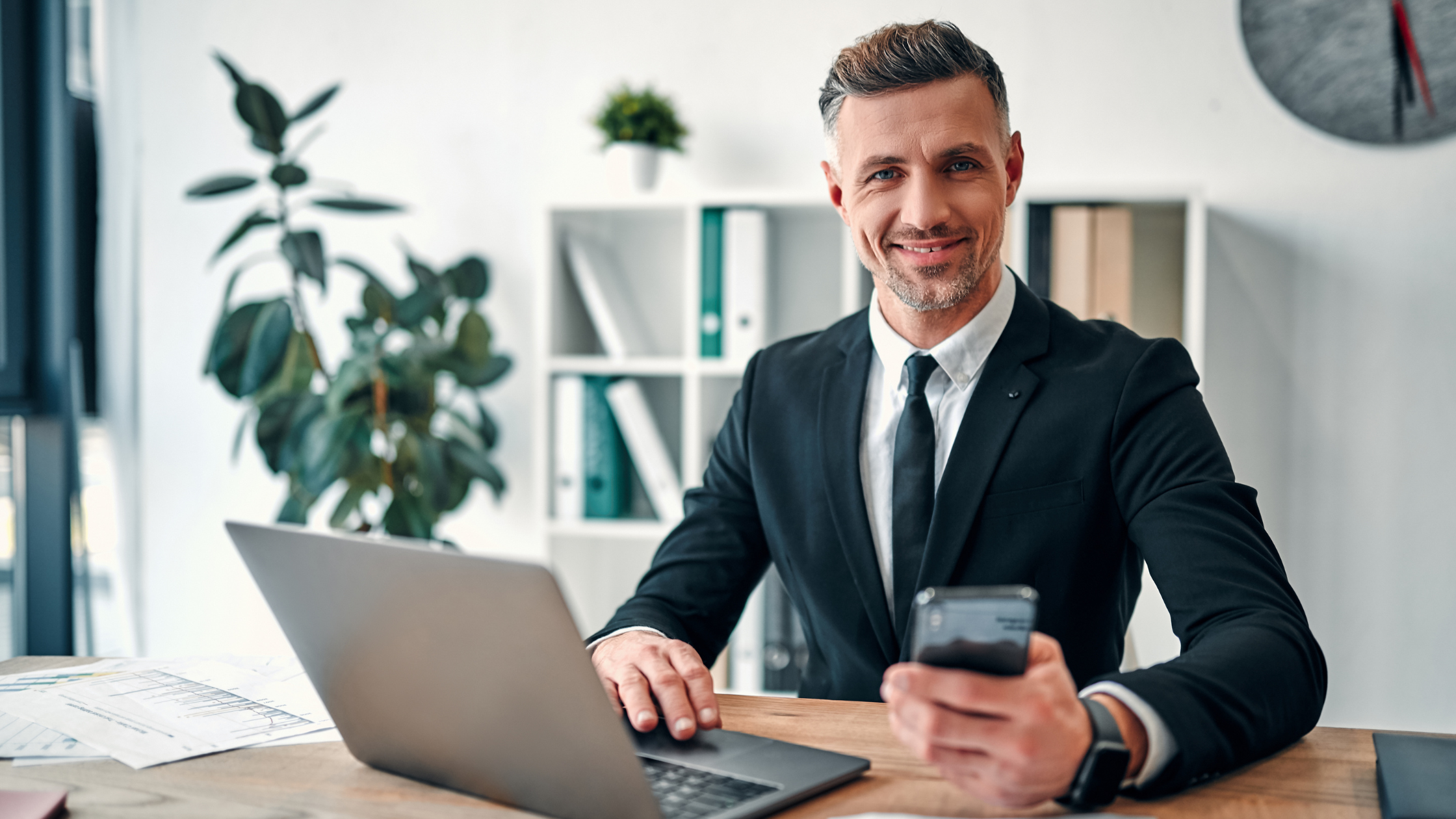 Business owner smiling at the camera while sitting at a desk with a computer keyboard.