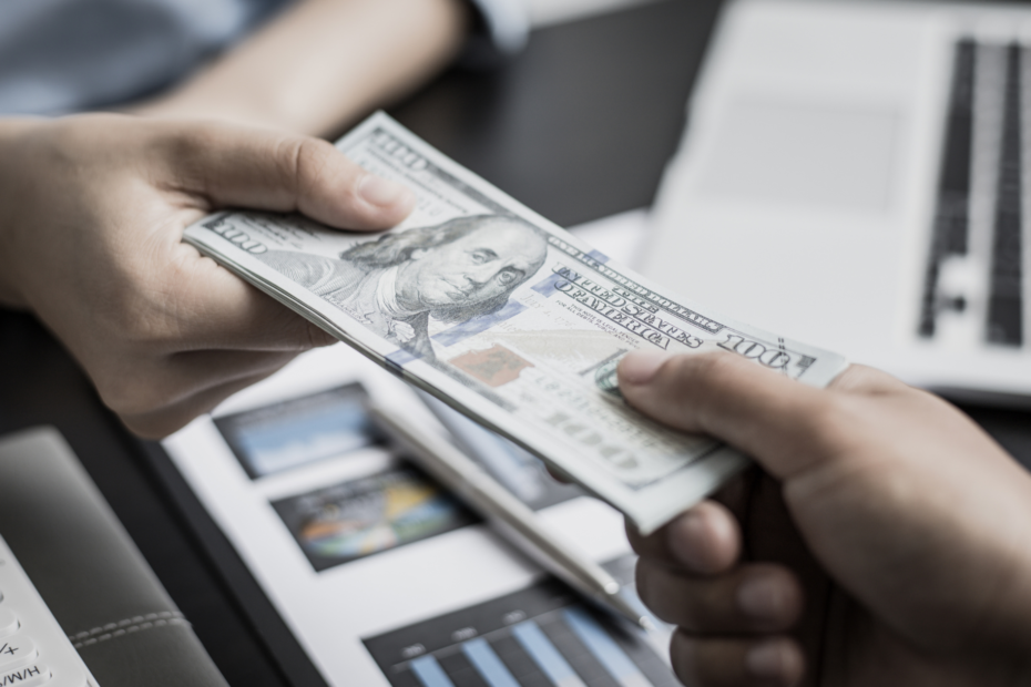 Two hands exchanging money across a desk.