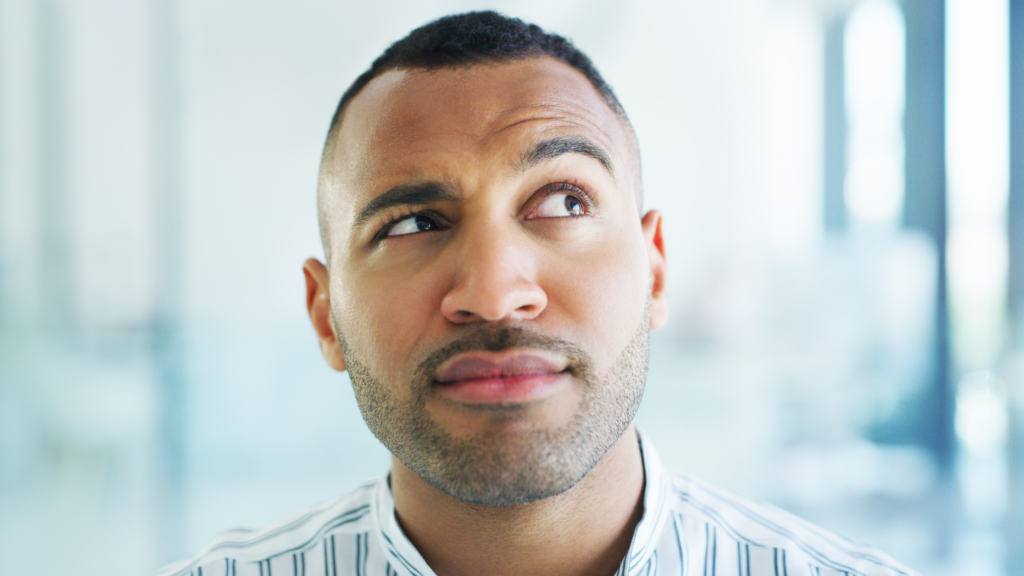 A man with one raised eyebrow, looking sideways with curiosity or skepticism.