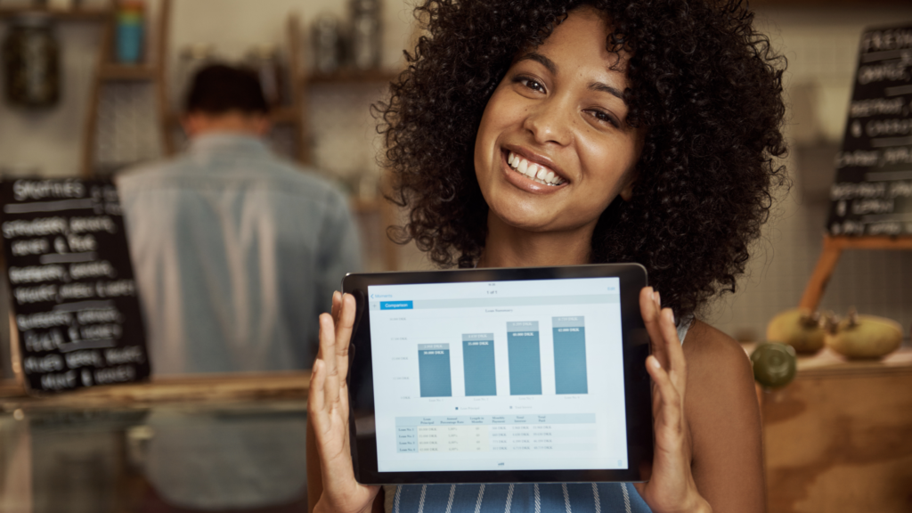 A woman displaying a graph of her business' growth in a cozy cafe setting.