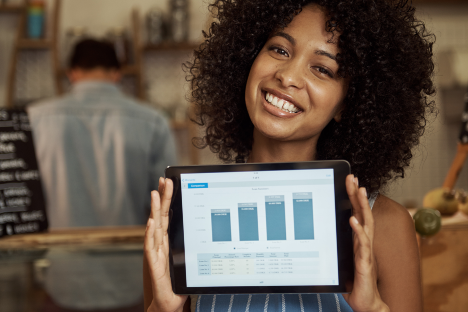 A woman displaying a graph of her business' growth in a cozy cafe setting.