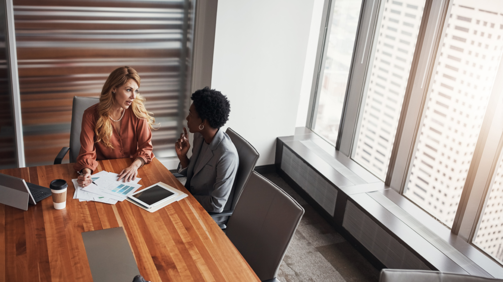 Two women engaged in a conversation in an office setting.