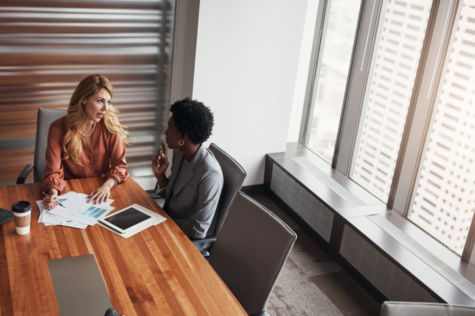 Two women engaged in a conversation in an office setting.