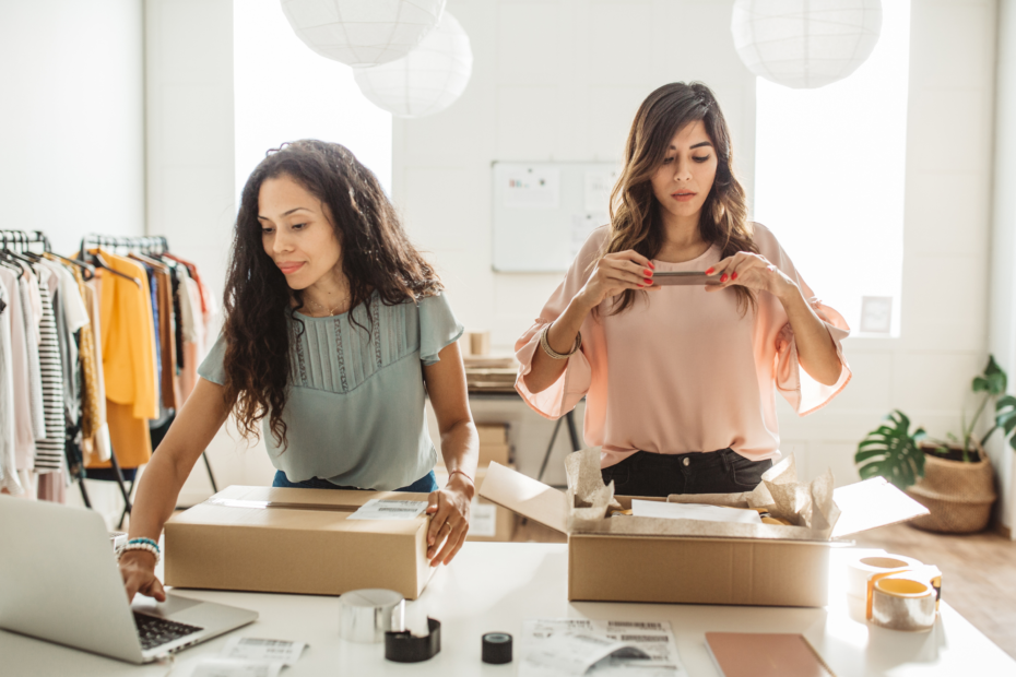 Two females working behind a counter in a light and airy clothing boutique.