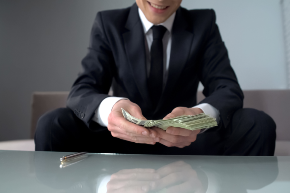 Business owner in a suit sitting at a table, counting out cash.