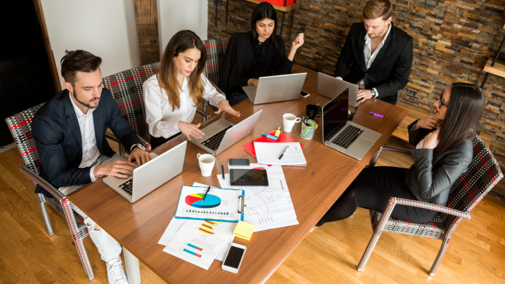 Five business people collaborating at a shared office table.