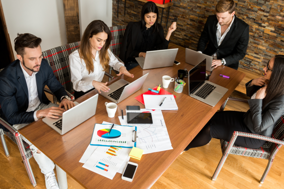 Five business people collaborating at a shared office table.