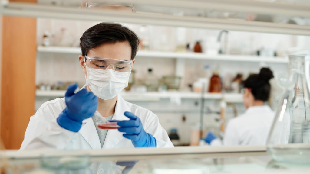 A lab technician is putting liquid into a beaker for biotech purposes.