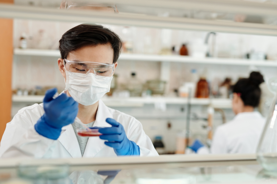 A lab technician is putting liquid into a beaker for biotech purposes.