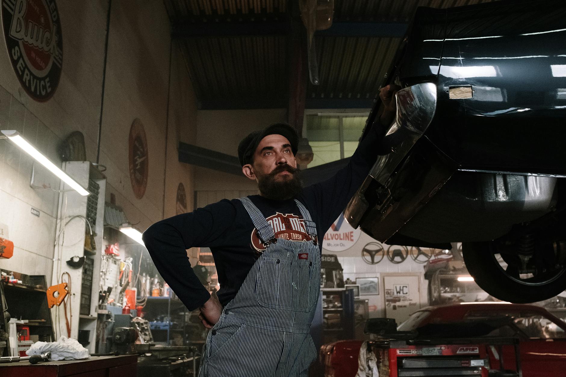 man in black long sleeve shirt and blue denim jeans standing beside black car