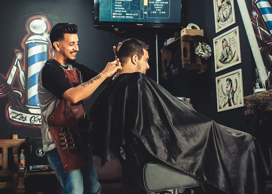 smiling man cutting another mans hair inside shop