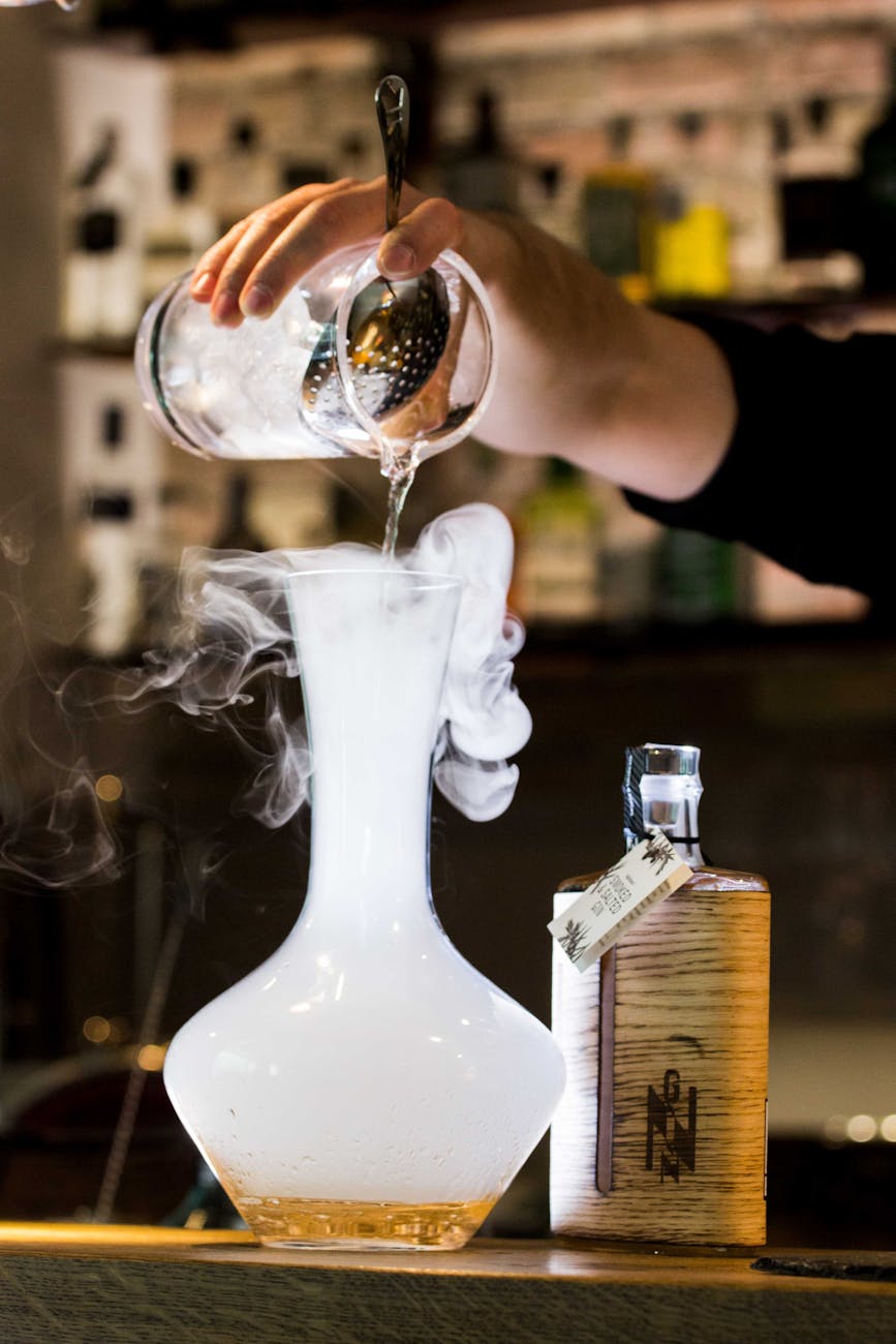 person pouring liquid into smoking glass container